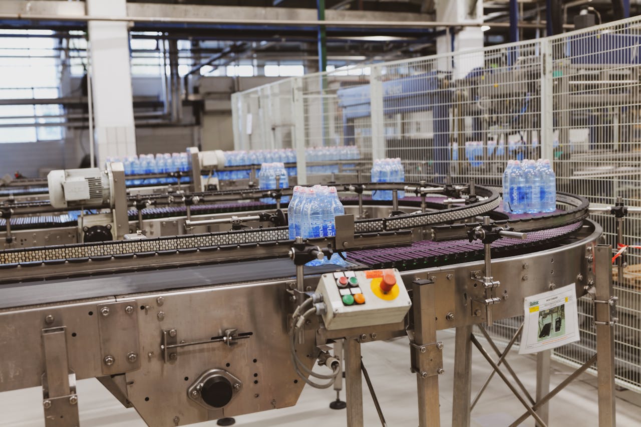 gallery-5 Water bottles being processed on an automated conveyor in a modern factory setting.