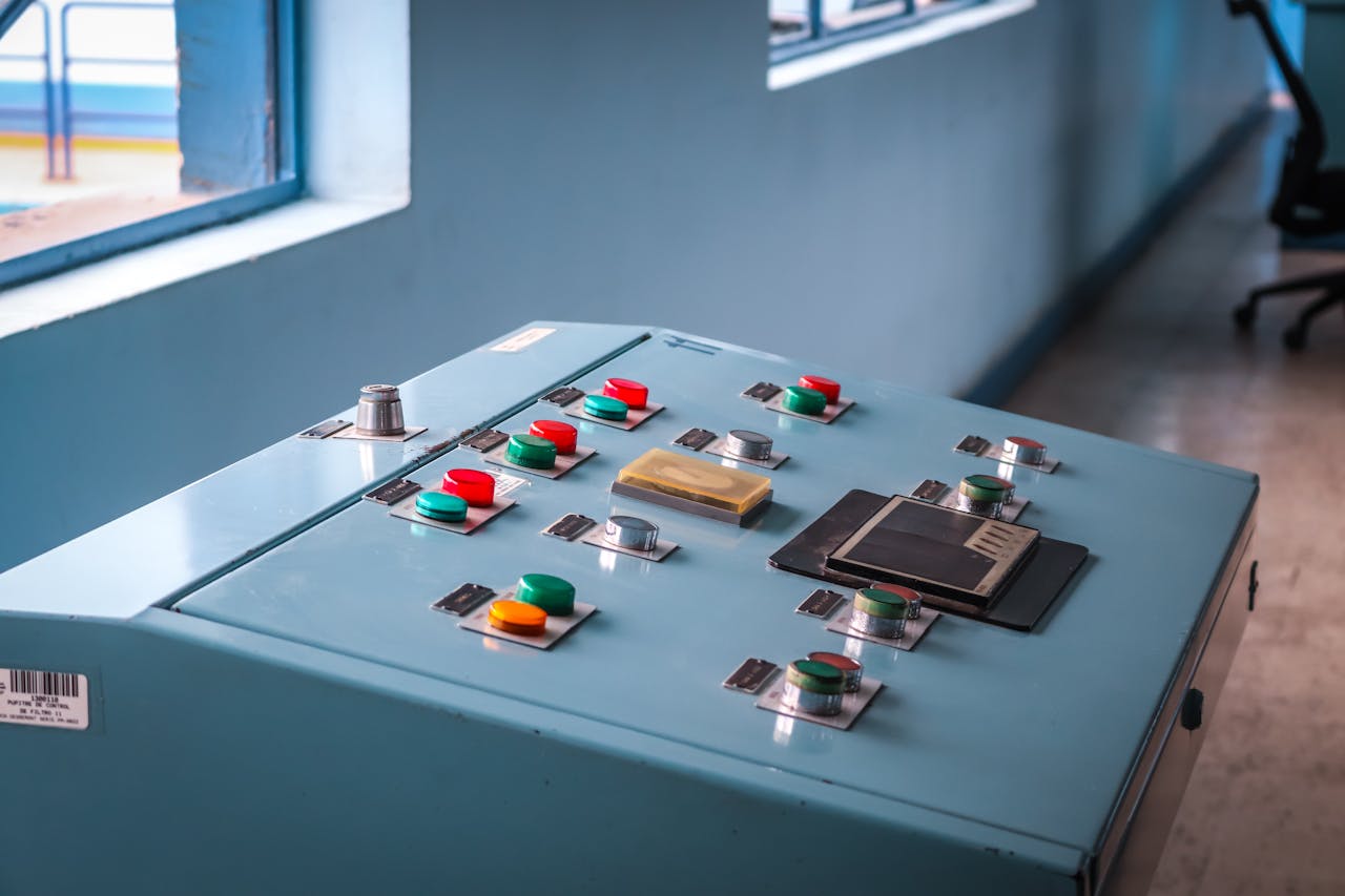 contact-img Close-up of an industrial control panel with colorful buttons in a factory setting.